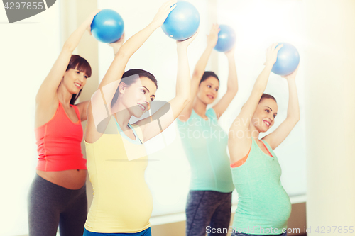 Image of happy pregnant women exercising with ball in gym