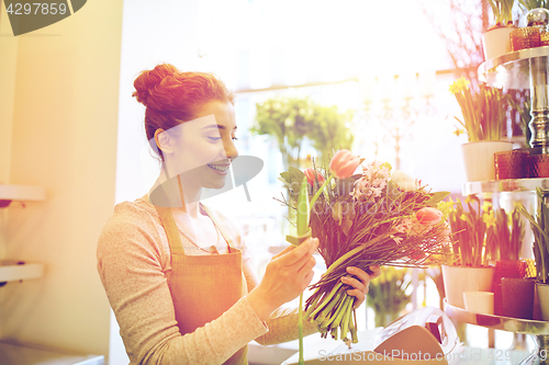 Image of smiling florist woman making bunch at flower shop