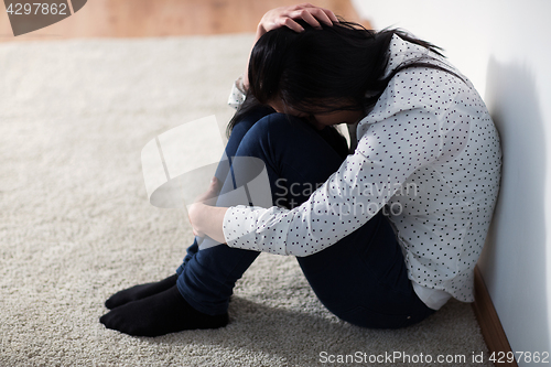 Image of unhappy woman crying on floor at home