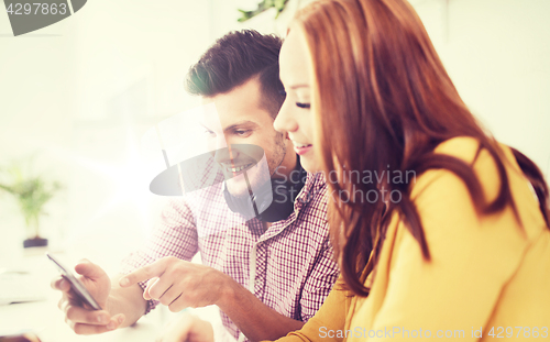 Image of happy creative team with smartphones at office