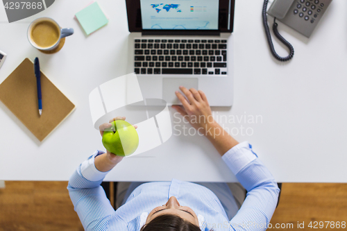 Image of businesswoman with apple and laptop at office