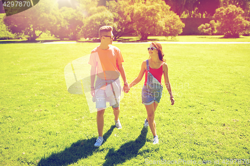 Image of happy teenage couple walking at summer park