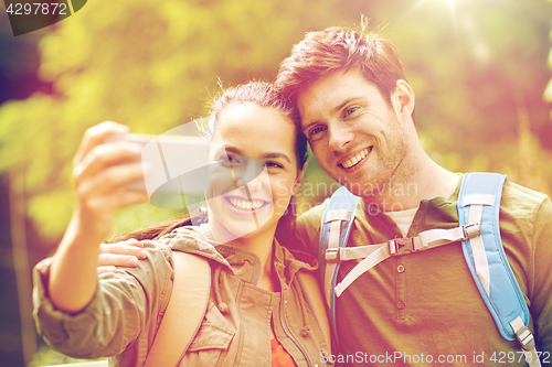 Image of couple with backpacks taking selfie by smartphone