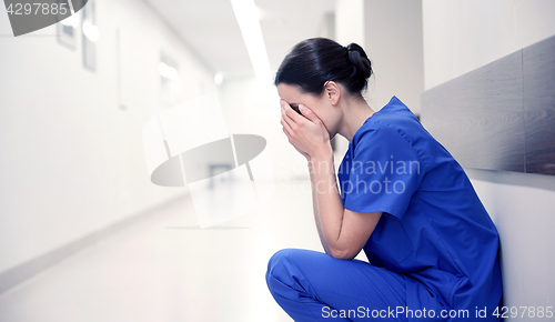 Image of sad or crying female nurse at hospital corridor