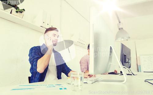 Image of happy creative man calling on cellphone at office