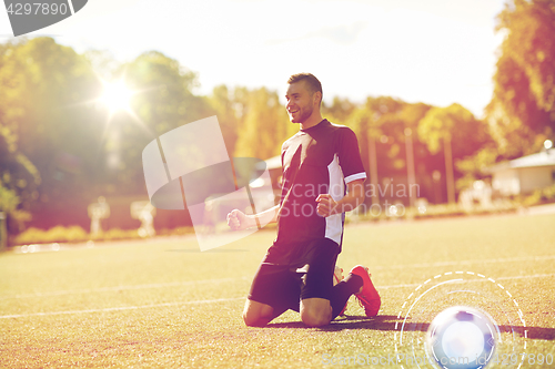 Image of happy soccer player with ball on football field