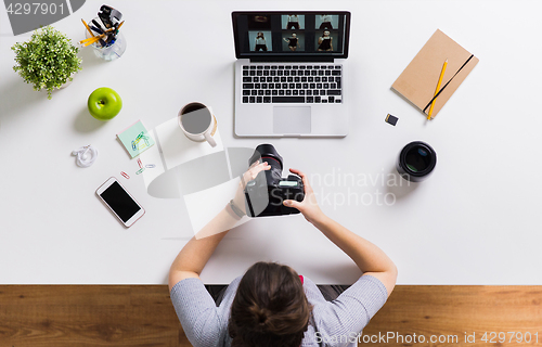 Image of woman with camera and laptop at office table