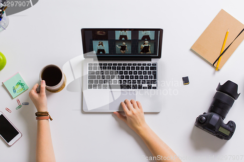 Image of woman hands with camera working on laptop at table