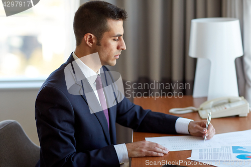 Image of businessman with papers working at hotel room