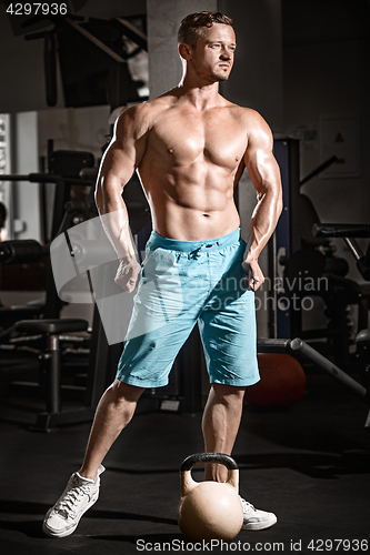 Image of Muscular bodybuilder guy doing exercises with weight in gym