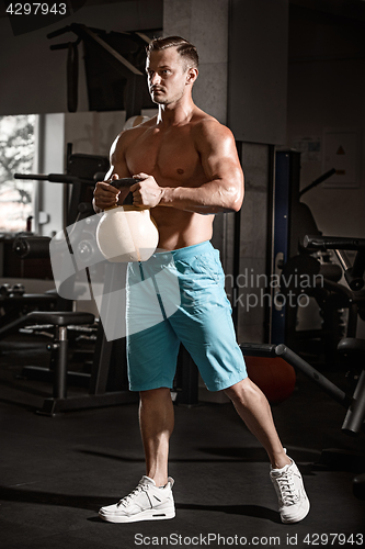 Image of Muscular bodybuilder guy doing exercises with weight in gym