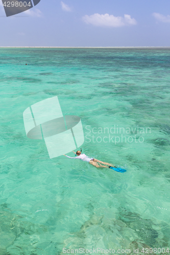 Image of Woman snorkeling in clear shallow sea of tropical lagoon with turquoise blue water.