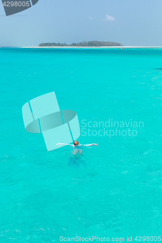 Image of Woman snorkeling in clear shallow sea of tropical lagoon with turquoise blue water.