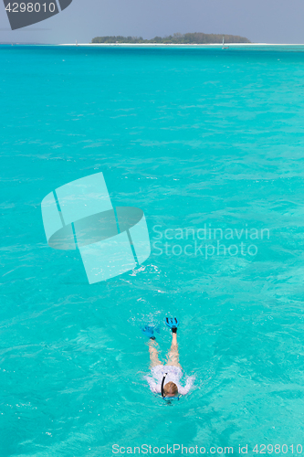 Image of Woman snorkeling in clear shallow sea of tropical lagoon with turquoise blue water.