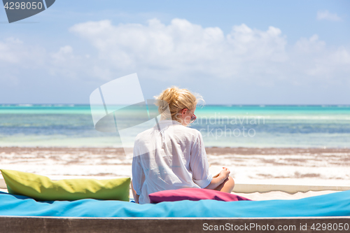 Image of Relaxed woman in luxury lounger, arms rised, enjoying summer vacations on beautiful beach.