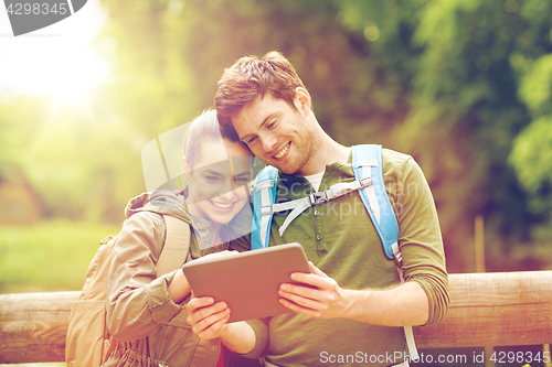 Image of happy couple with backpacks and tablet pc outdoors