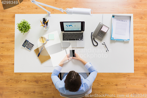 Image of businesswoman with laptop and smartphone at office