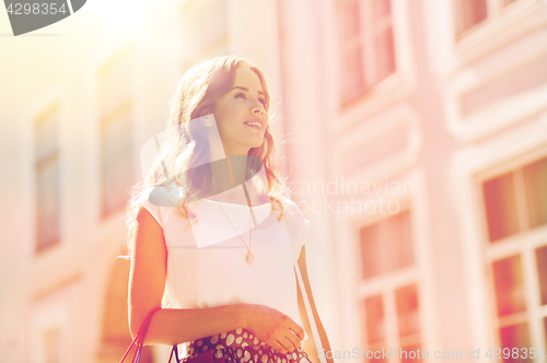 Image of happy woman with shopping bags walking in city 