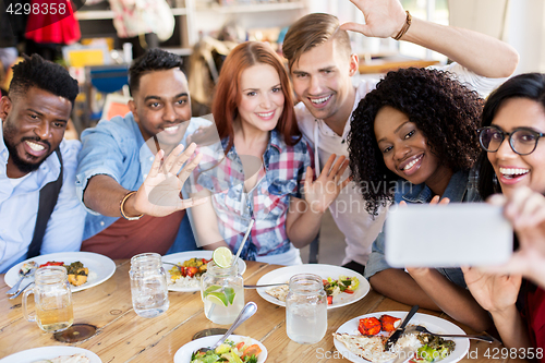 Image of friends eating and taking selfie at restaurant