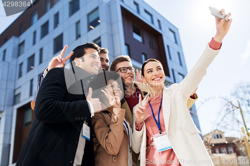 Image of happy people with conference badges taking selfie