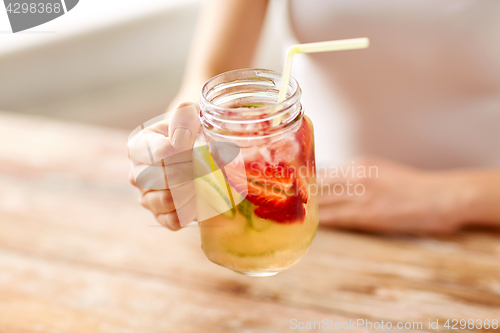 Image of close up of woman holding glass with fruit water