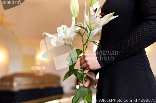 Image of close up of woman with lily flowers at funeral