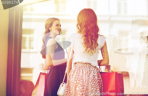 Image of happy women with shopping bags at shop window