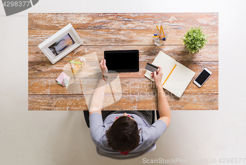 Image of woman with tablet pc and credit card at table