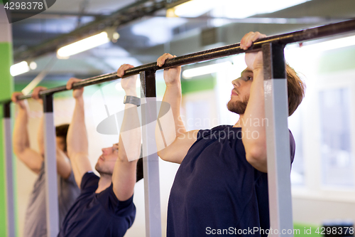 Image of group of young men doing pull-ups in gym