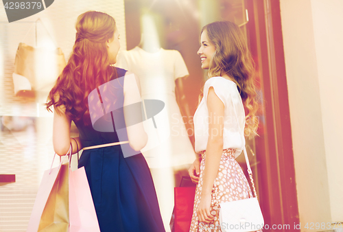 Image of happy women with shopping bags at shop window