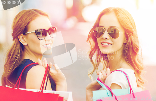 Image of happy young women with shopping bags in city
