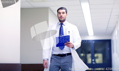 Image of doctor with clipboard walking along hospital