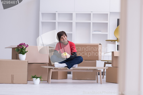 Image of boy sitting on the table with cardboard boxes around him