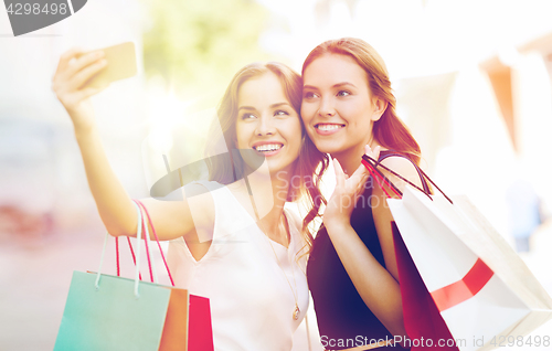 Image of happy women with shopping bags and smartphone