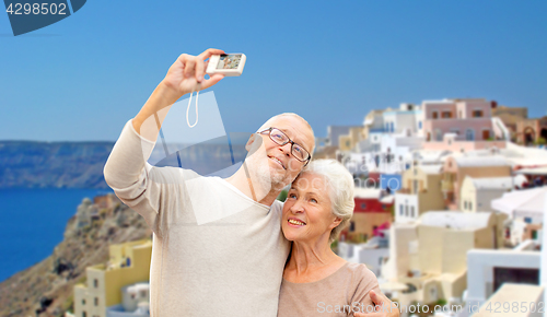 Image of senior couple with camera travelling in santorini