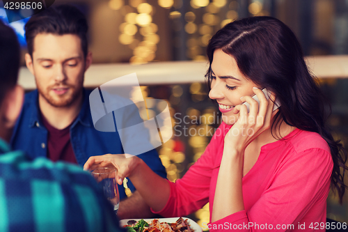 Image of woman with smartphone and friends at restaurant