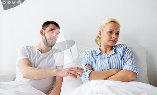 Image of unhappy couple having conflict in bed at home