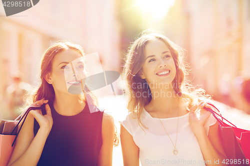 Image of happy women with shopping bags walking in city 