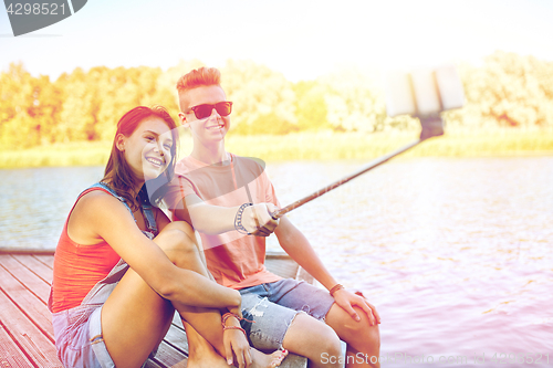 Image of happy teenage couple taking selfie on smartphone