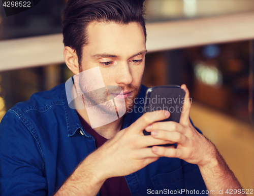 Image of man with smartphone reading message at restaurant