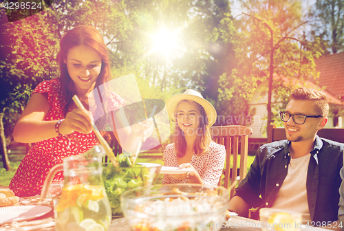 Image of happy friends having dinner at summer garden party