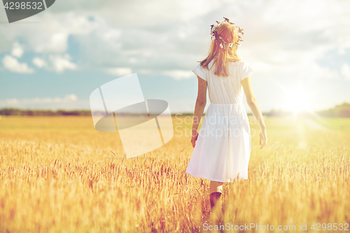 Image of happy young woman in flower wreath on cereal field