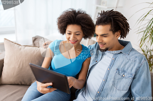 Image of smiling happy couple with tablet pc at home