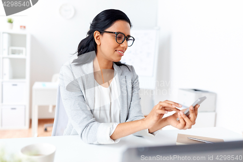 Image of businesswoman messaging on smartphone at office