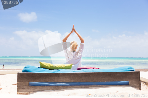 Image of Relaxed woman in luxury lounger, arms rised, enjoying summer vacations on beautiful beach.