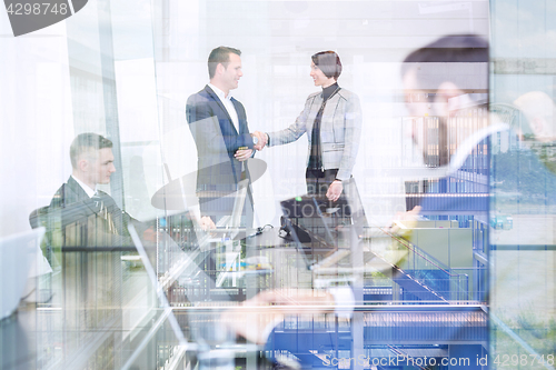 Image of Business people shaking hands in moder corporate office.