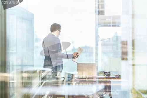 Image of Businessman talking on a mobile phone while looking through window.