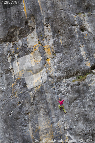 Image of Strong girl climbs on a rock, doing sports climbing in nature.