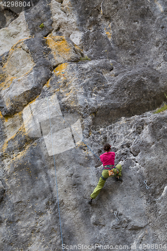 Image of Strong girl climbs on a rock, doing sports climbing in nature.