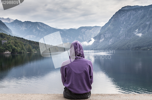 Image of Sporty woman watching tranquil overcast morning scene at lake Bohinj, Alps mountains, Slovenia.